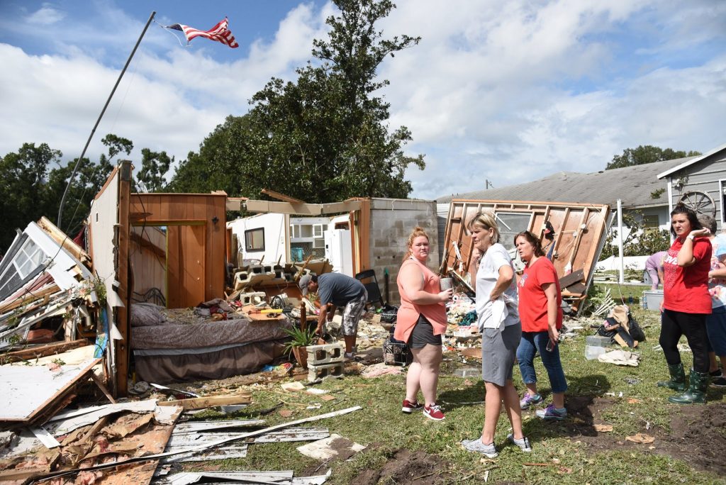 Residents standing next to storm disaster damaged structures